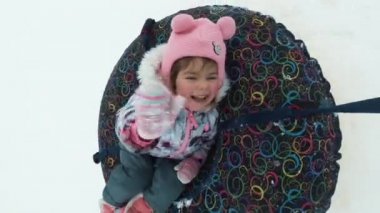 kış, boş zaman ve eğlence kavramı - bir kızağa yalan ve hareketi sırasında sallayarak mutlu küçük kız.