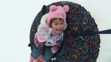 kış, boş zaman ve eğlence kavramı - bir kızağa yalan ve hareketi sırasında sallayarak mutlu küçük kız.