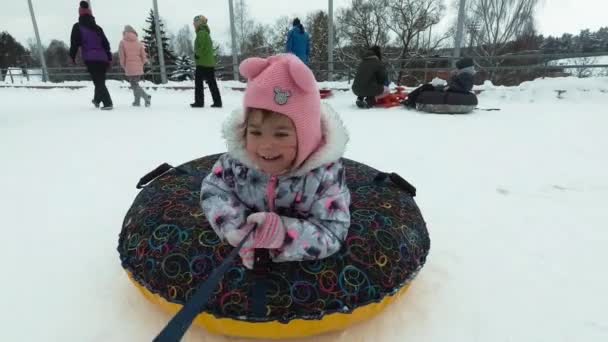 Inverno, svago e divertimento concetto - felice bambina sdraiata su una slitta e agitando durante il movimento . — Video Stock