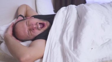 Adam uyuyan bir çift kişilik yatak uyanır. Yan görünüm, orta vurdu.