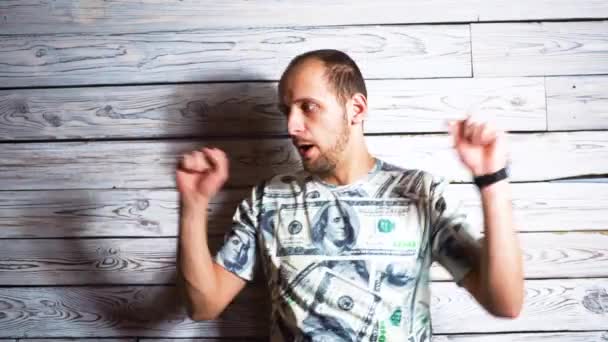 Сумасшедший счастливый человек в футболке с долларом радуется успеху Улыбается и прыгает от радости. Концепция на тему неожиданного богатства, богаче . — стоковое видео
