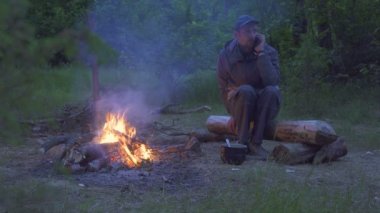 Adam birisiyle konuşuyor bir arar ve gülümseyerek telefonu tıklatır. Gezgin ateşin yanında oturmuş telefonda konuşuyor.