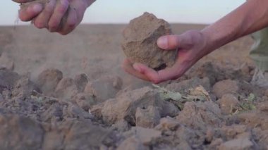 Yavaş çekim videosunda insanların elleri toprak tozu tutuyor. Kuraklık, yağmursuz topraklar