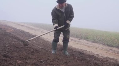 üst düzey çiftçi şapkalı bir çamurlu çapa ve dirgen alanı oluşturuldu. El İşçiliği. Sis