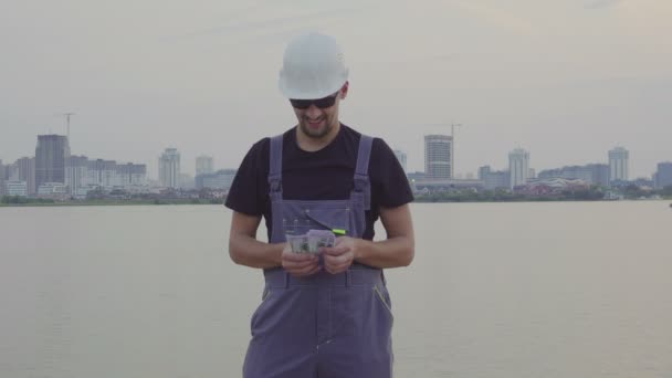 Bouwer telt geld in de stad van de mooie avond buiten — Stockvideo