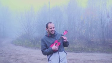 Portre yakışıklı adam parkta, müzik konsepti bas gitar çalmaya.