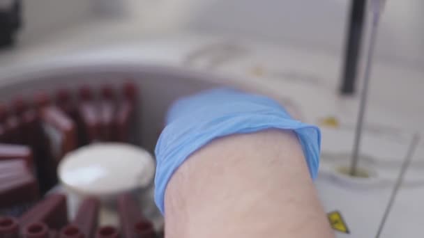 Um funcionário do laboratório a fazer um exame de sangue. carrega os tubos na máquina. O assistente que carrega o frasco para injetáveis nas centrífugas do laboratório. Alteração dos frascos de sangue . — Vídeo de Stock