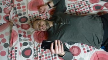 Sabahleyin yatakta Smartphone kullanan genç adam