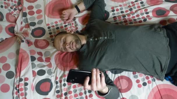 Joven usando smartphone en la cama por la mañana — Vídeos de Stock