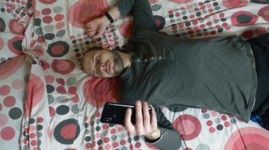 Sabahleyin yatakta Smartphone kullanan genç adam