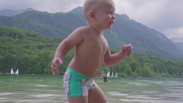 Αγοράκι 2 ετών στο νερό της λίμνης ορεινό δάσος. Θέα από το πίσω μέρος. — Αρχείο Βίντεο