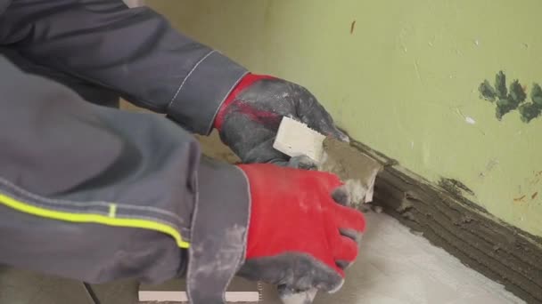 Werknemer stelt kleine tegels op de muur in de keuken. Zijn handen zijn het plaatsen van de tegel op de lijm. stedikam schieten — Stockvideo