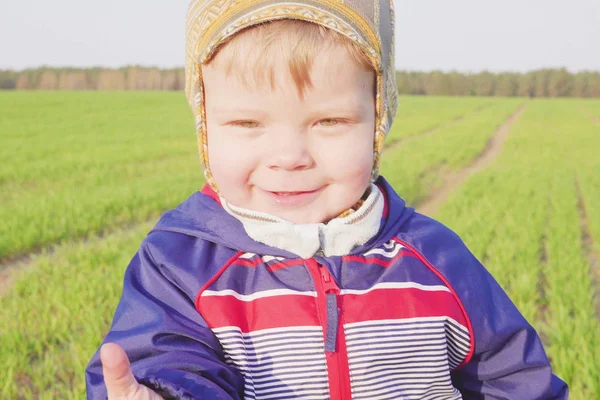 one year old boy farmer going in the field with young wheat. Closeup