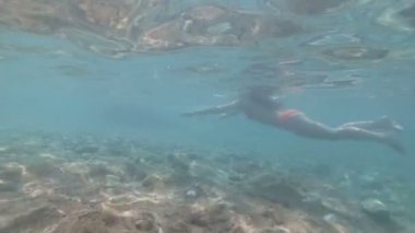 Güzel şekil kızla sahilde yüzüyor. Sualtı çekim.