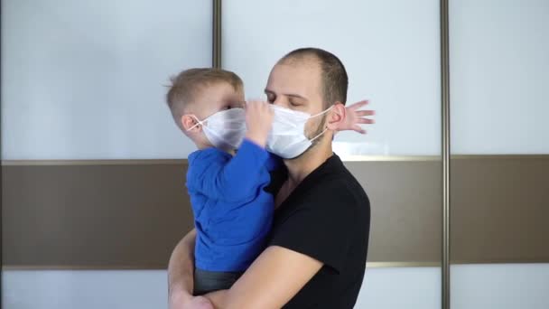 Portret van vader bedrijf schattige kleine peuter baby jongenskind dragen van beschermende medische masker, vader en zoon permanent in kliniek — Stockvideo