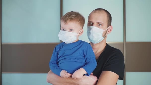 Портрет отца с милым маленьким малышом, мальчик в защитной медицинской маске, папа и сын стоят в клинике — стоковое видео