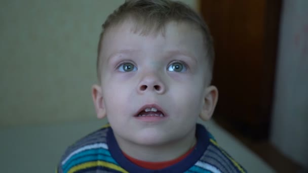 Nahaufnahme eines zweijährigen Jungen, der auf einem Heimprojektor Film schaut. — Stockvideo
