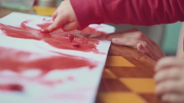 Handen van de kinderen maken gekleurde handafdrukken op witte achtergrond. Bovenaanzicht, plat lag. — Stockvideo