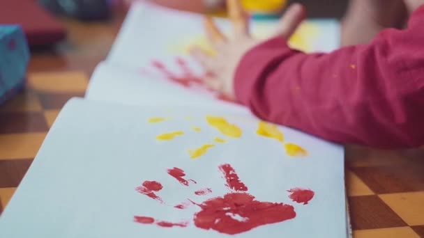 Kids hænder gør farvede håndaftryk på hvid baggrund. Top udsigt, flad lå . – Stock-video
