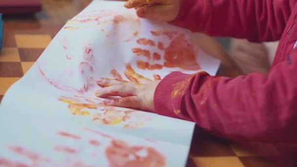 Kids hands making colored handprints on white background. Top view, flat lay. — Stock Video