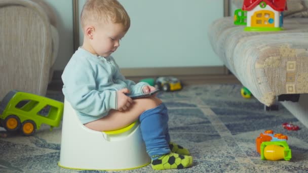 Adorable boy with a smartphone during potty training on the room. — Stock Video