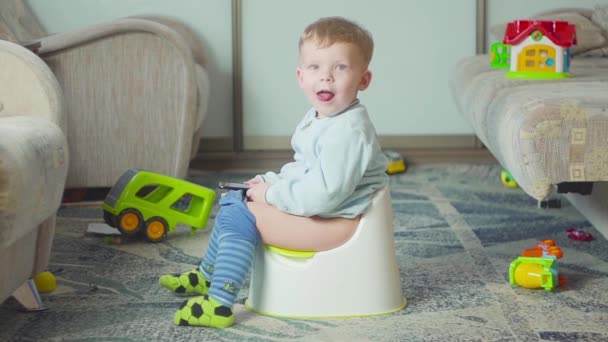 Adorable boy with a smartphone during potty training on the room. — Stock Video