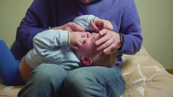 Un padre cercano le mete medicina en el oído a un chico enfermo . — Vídeos de Stock