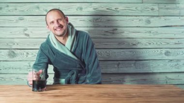 Bira ve Sauna. Banyo ve spa. Bornozlu yakışıklı adam bira içme ve tost söyleyerek.