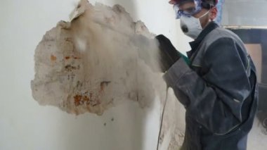 işçi koruyucu kıyafetli alçı duvar yıkan. Kirli, zor iş. Kişisel koruyucu donanım. Kask, maske ve gözlük.