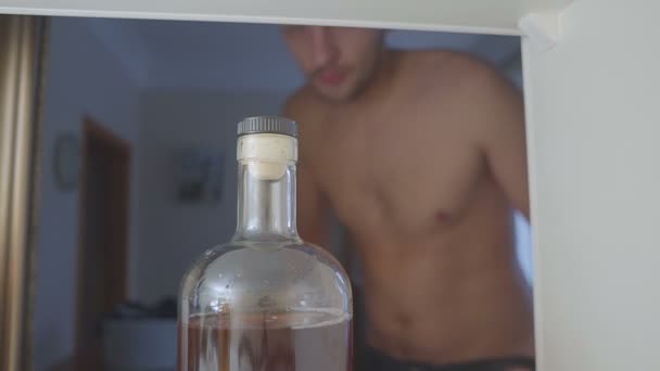 Alkoholist utan T-shirt drycker alkohol från en flaska i garderoben. ledsna hem soffan i alkohol missbruk och alkoholism koncept. — Stockvideo