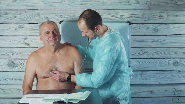 Klinikte kıdemli bir hastayla çalışan genç bir fizyoterapist. Ağrıyan kolun muayenesi.