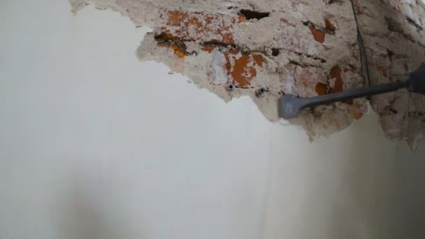 Worker in protective suit demolishes plaster wall. Punch and falling plaster close-up. — Stock Video