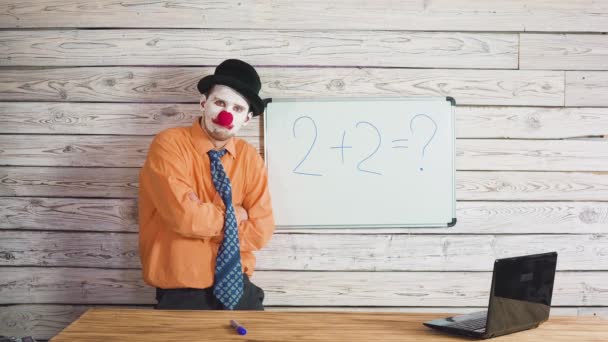 Retrato de lindo payaso masculino cerca de la escuela o pizarra de estudiantes. Estúpido profesor explicando a los estudiantes la tarea — Vídeos de Stock