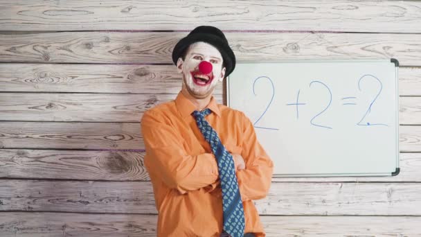 Porträt eines niedlichen männlichen Clowns in der Nähe der Schultafel oder der Schülertafel. Dumme Lehrer erklären Schülern die Aufgabe — Stockvideo