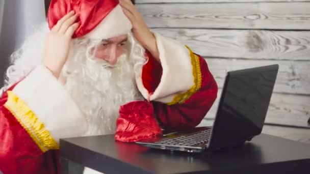 Papai Noel trabalhando com laptop em um escritório. Papai Noel usando um smartphone — Vídeo de Stock