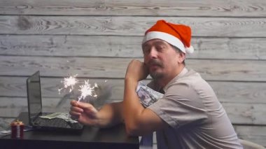 bengal ile Noel şapkalı bir rüya gibi adam ateş maytap ve laptop onun ellerinde. Düşen para dolar.