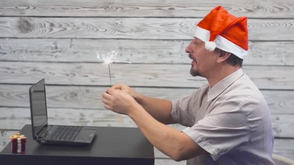 Homem sonhador em um chapéu de Natal com fogo bingalês e laptop em suas mãos. Caindo Dólares Dinheiro . — Vídeo de Stock