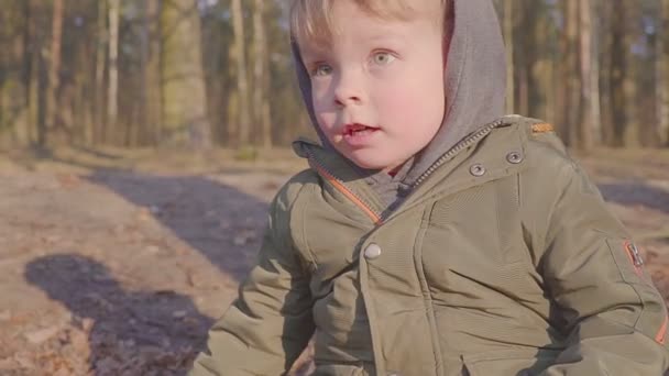 Um rapaz está a correr pela floresta perto de casas particulares. Retrato de um rapaz feliz. Noite de primavera ou outono . — Vídeo de Stock