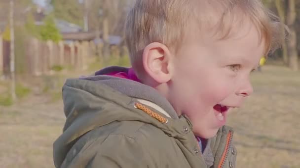 En pojke springer genom skogen. Porträtt av en lycklig pojke. Vår-eller höst kväll. — Stockvideo