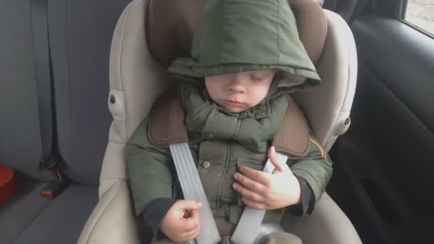 車の後部座席にいる小さな男の子が眠りに落ち始める。その車は悪路になっている。赤ちゃんと一緒に旅行 — ストック動画