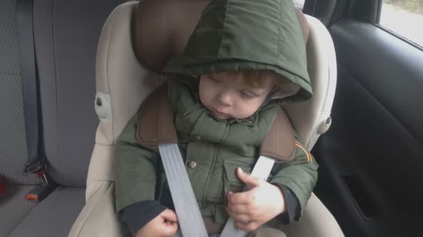 Liten pojke i bak sätet på en bil börjar somna. Bilen går på en dålig väg. Resa med baby — Stockvideo