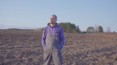 Tarlada duran ve kendi topraklarına bakan çiftçi adamın yakın portresi