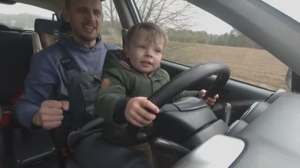 Father teaches two year old son to drive car. — Stock Video