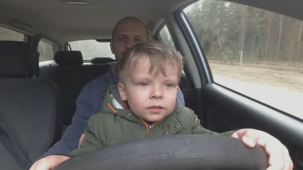 Father teaches two year old son to drive car. — Stock Video