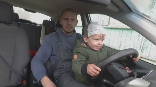 Otec učí dva roky starý syn řídit auto. — Stock video