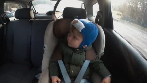 Petit garçon dans un siège enfant dans la voiture. Temps écoulé. Rythme de la grande ville — Video