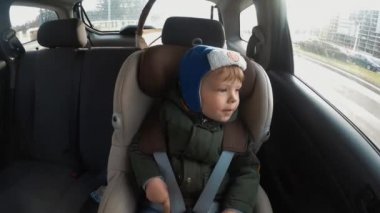 Arabada çocuk koltuğunda oturan küçük çocuk. Zaman atlamalı. Büyük şehir ritmi