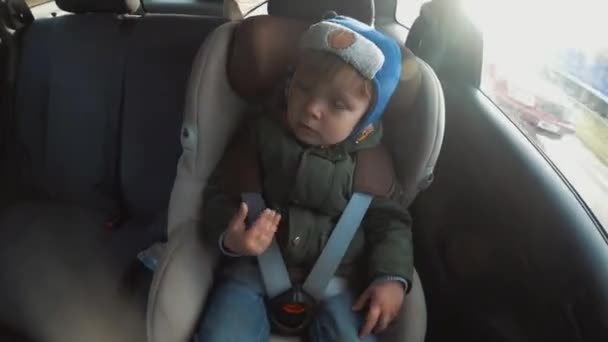 Маленький мальчик в детском кресле в машине. Время истекло. Большой городской ритм — стоковое видео