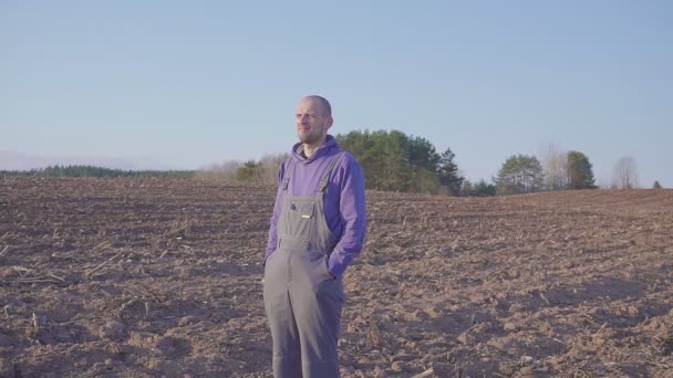 Cerca de retrato del hombre agricultor de pie en el campo y mirando a su territorio — Vídeos de Stock