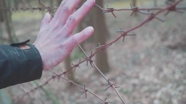 Bir adamın eli dikenli tellere dokunur. Kavram yasadışı göç. Avrupa'ya göç etmek isteyen bir Arap. Gurbetçiler için Kamp.